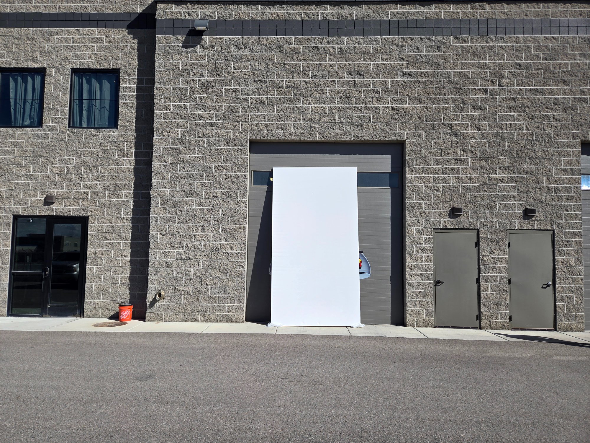 Two people holding a massive portrait-oriented blank canvas